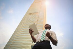 Photo by Bruce Mars on Unsplash. Man wearing tie standing in front of a business tower.